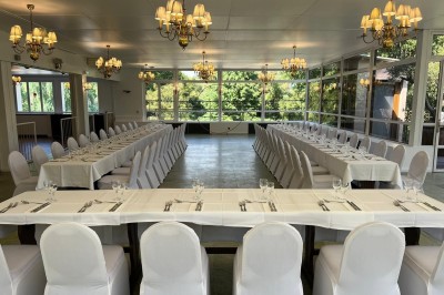 Buffet décoré avec des ballons roses et blancs, plats variés, et un cochon rôti sur une table drapée de blanc.