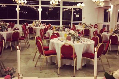 Buffet décoré avec des ballons roses et blancs, plats variés, et un cochon rôti sur une table drapée de blanc.