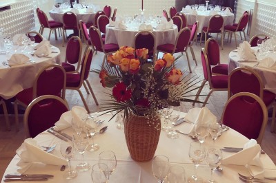 Buffet décoré avec des ballons roses et blancs, plats variés, et un cochon rôti sur une table drapée de blanc.