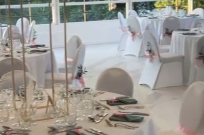 Buffet décoré avec des ballons roses et blancs, plats variés, et un cochon rôti sur une table drapée de blanc.