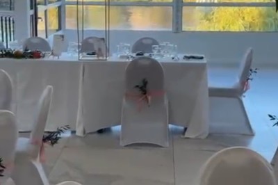 Buffet décoré avec des ballons roses et blancs, plats variés, et un cochon rôti sur une table drapée de blanc.