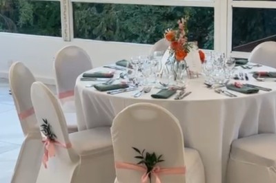 Buffet décoré avec des ballons roses et blancs, plats variés, et un cochon rôti sur une table drapée de blanc.
