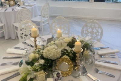 Buffet décoré avec des ballons roses et blancs, plats variés, et un cochon rôti sur une table drapée de blanc.