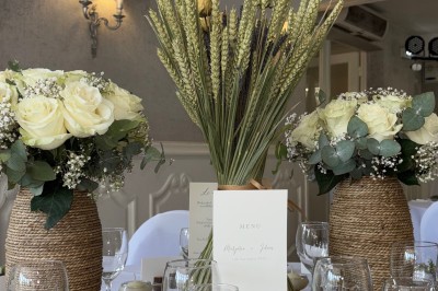 Buffet décoré avec des ballons roses et blancs, plats variés, et un cochon rôti sur une table drapée de blanc.