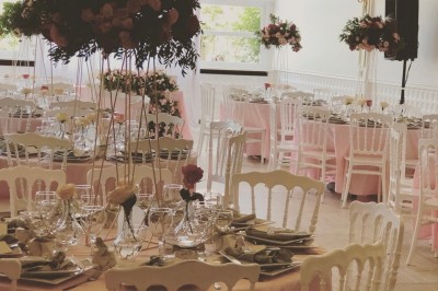 Buffet décoré avec des ballons roses et blancs, plats variés, et un cochon rôti sur une table drapée de blanc.