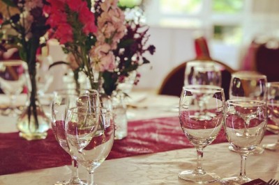 Buffet décoré avec des ballons roses et blancs, plats variés, et un cochon rôti sur une table drapée de blanc.