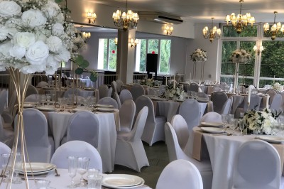 Buffet décoré avec des ballons roses et blancs, plats variés, et un cochon rôti sur une table drapée de blanc.