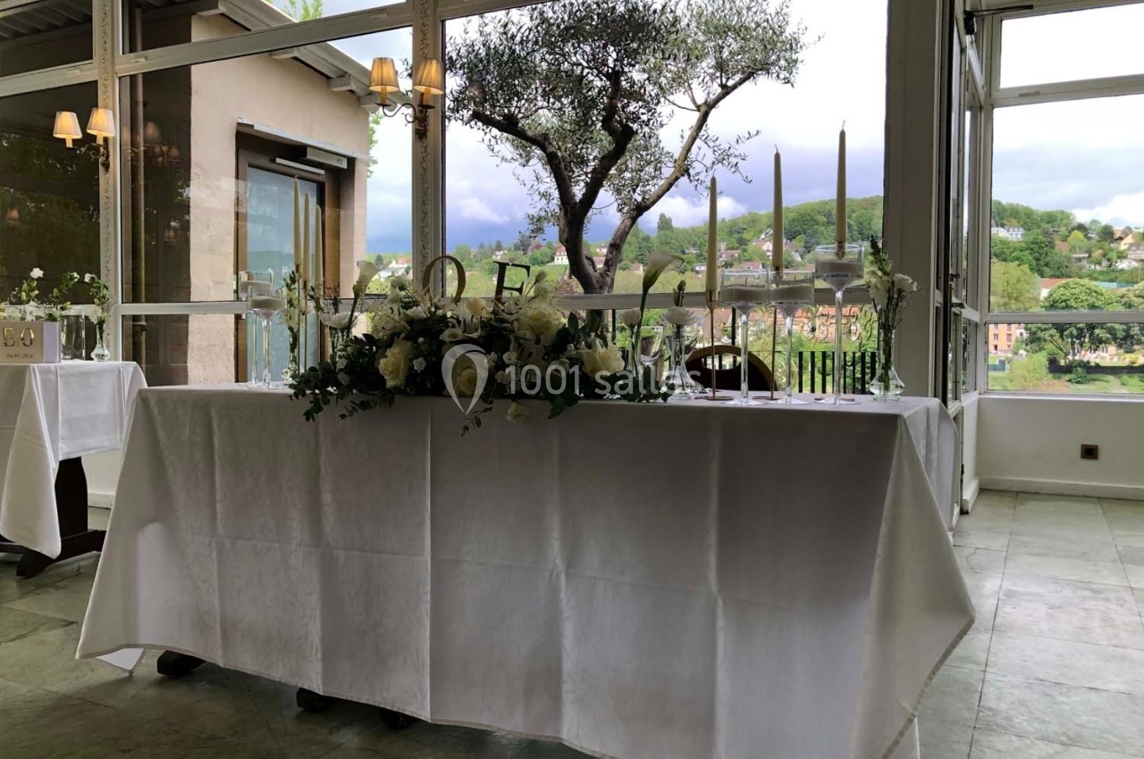 Table décorée avec des fleurs blanches et des bougies, placée devant une baie vitrée offrant une vue sur un paysage…