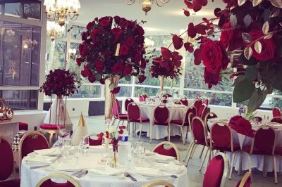 Buffet décoré avec des ballons roses et blancs, plats variés, et un cochon rôti sur une table drapée de blanc.