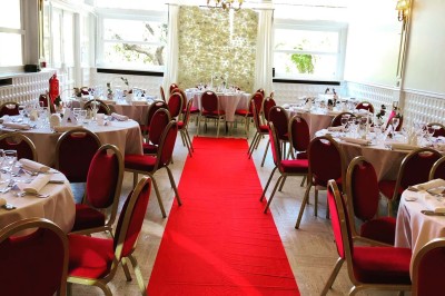Buffet décoré avec des ballons roses et blancs, plats variés, et un cochon rôti sur une table drapée de blanc.