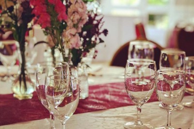 Buffet décoré avec des ballons roses et blancs, plats variés, et un cochon rôti sur une table drapée de blanc.