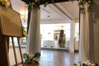 Buffet décoré avec des ballons roses et blancs, plats variés, et un cochon rôti sur une table drapée de blanc.