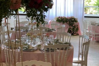Buffet décoré avec des ballons roses et blancs, plats variés, et un cochon rôti sur une table drapée de blanc.