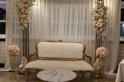 Buffet décoré avec des ballons roses et blancs, plats variés, et un cochon rôti sur une table drapée de blanc.