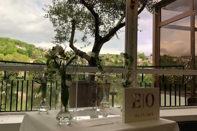 Buffet décoré avec des ballons roses et blancs, plats variés, et un cochon rôti sur une table drapée de blanc.