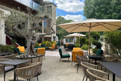 Groupe de personnes rassemblées en extérieur près d'une rivière, entourées de verdure et de stands d'exposition.