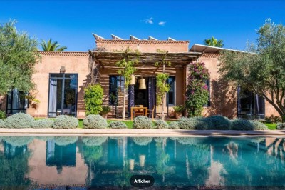 Miniature Location salle Marrakech (Province de Marrakech) - The Source #87 Reflet d'arbres et d'un bâtiment dans un bassin calme sous un ciel bleu dégagé.