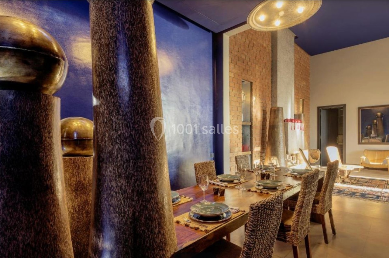 Salle à manger élégante avec table en bois, chaises tressées, décorations dorées et éclairage chaleureux.