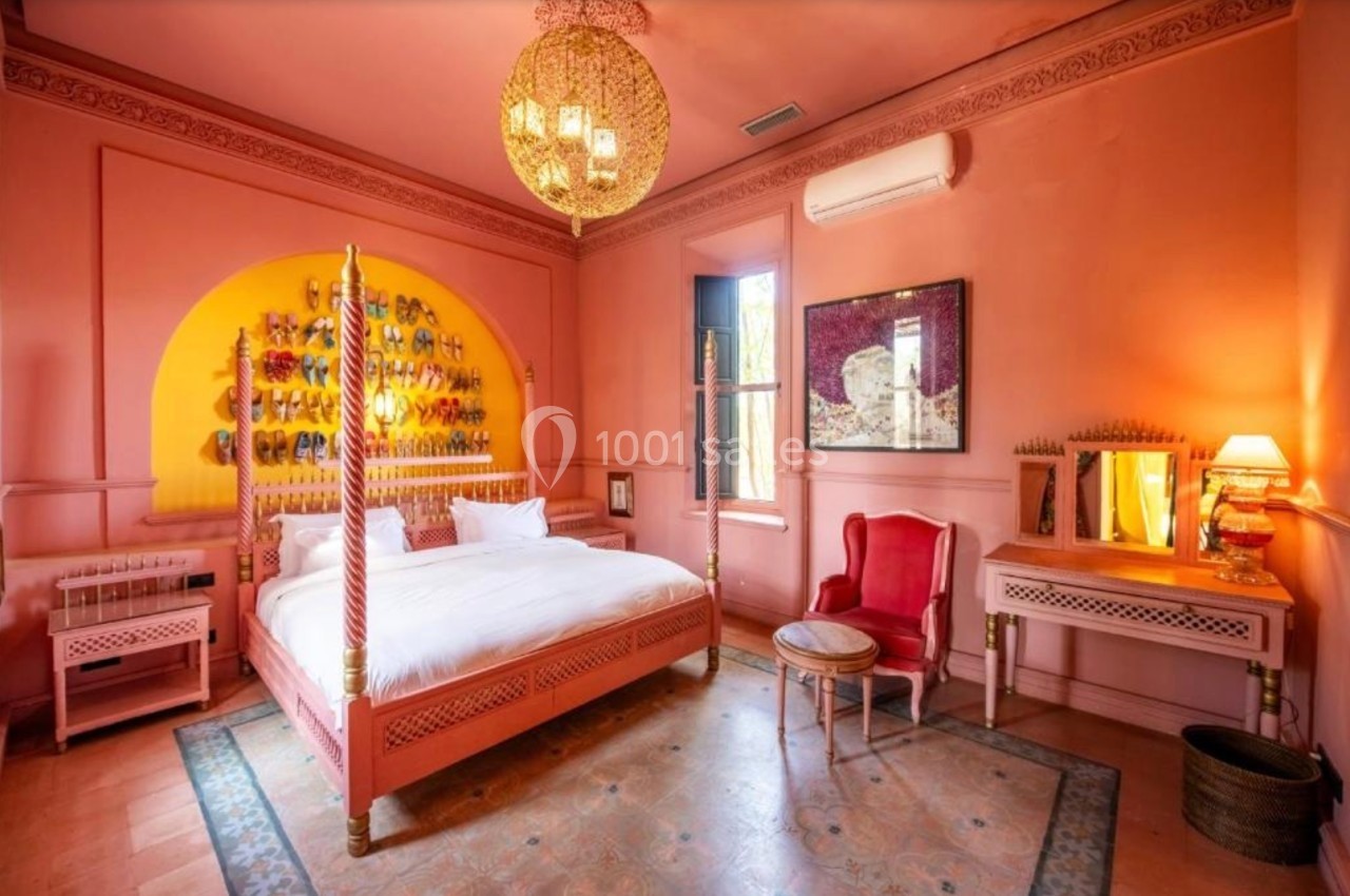 Chambre décorée dans des tons roses avec un lit à baldaquin, des meubles assortis et un éclairage chaleureux.