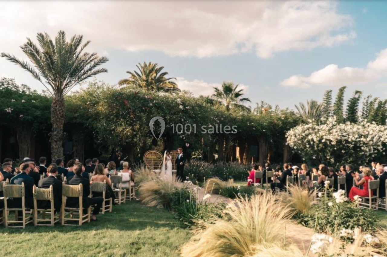 Cérémonie de mariage en plein air avec invités assis, entourée de végétation luxuriante et ciel dégagé.