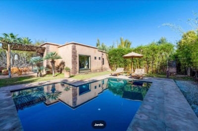 Miniature Location salle Marrakech (Province de Marrakech) - The Source #111 Reflet d'arbres et d'un bâtiment dans un bassin calme sous un ciel bleu dégagé.