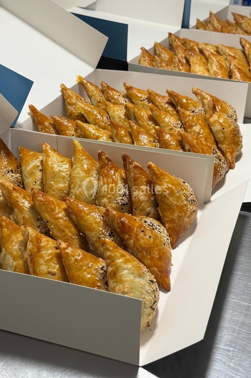 Assortiment de feuilletés dorés alignés dans des boîtes ouvertes, prêts à être servis.