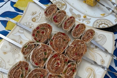 Un homme cuisine de grandes pièces de viande dans une marmite fumante en extérieur, portant un tablier et des gants.