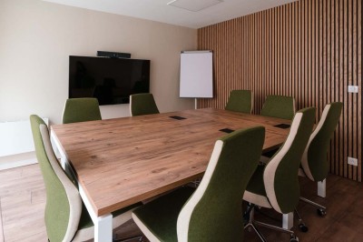 Une femme travaille sur un ordinateur dans un bureau moderne avec un mur décoré de motifs végétaux.