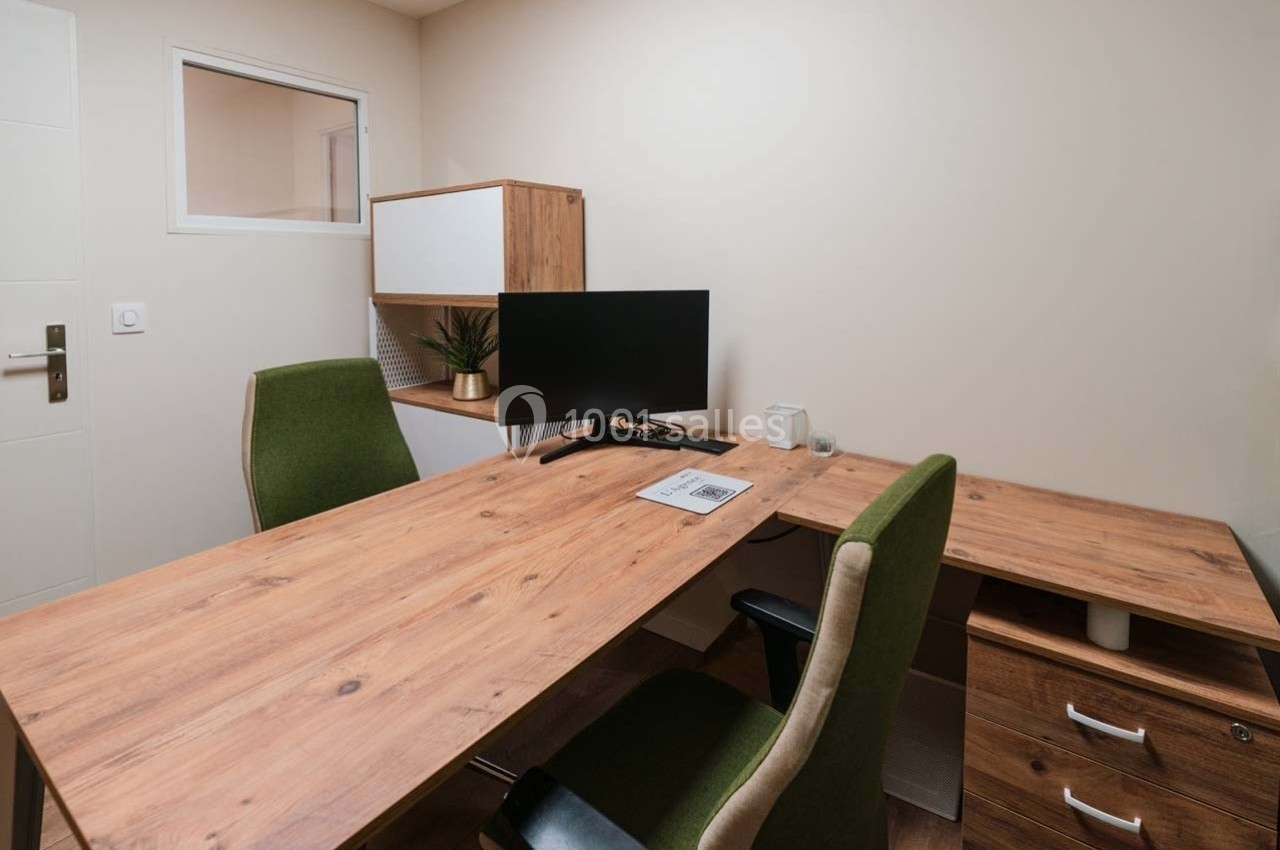 Bureau moderne avec deux chaises, un écran d'ordinateur, un bureau en bois et des rangements dans une pièce lumineuse.