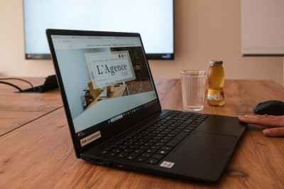 Une femme travaille sur un ordinateur dans un bureau moderne avec un mur décoré de motifs végétaux.