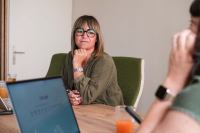 Une femme travaille sur un ordinateur dans un bureau moderne avec un mur décoré de motifs végétaux.