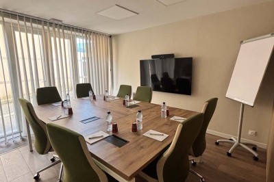 Une femme travaille sur un ordinateur dans un bureau moderne avec un mur décoré de motifs végétaux.