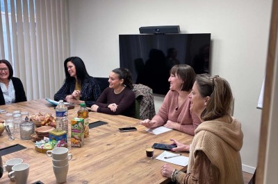 Une femme travaille sur un ordinateur dans un bureau moderne avec un mur décoré de motifs végétaux.