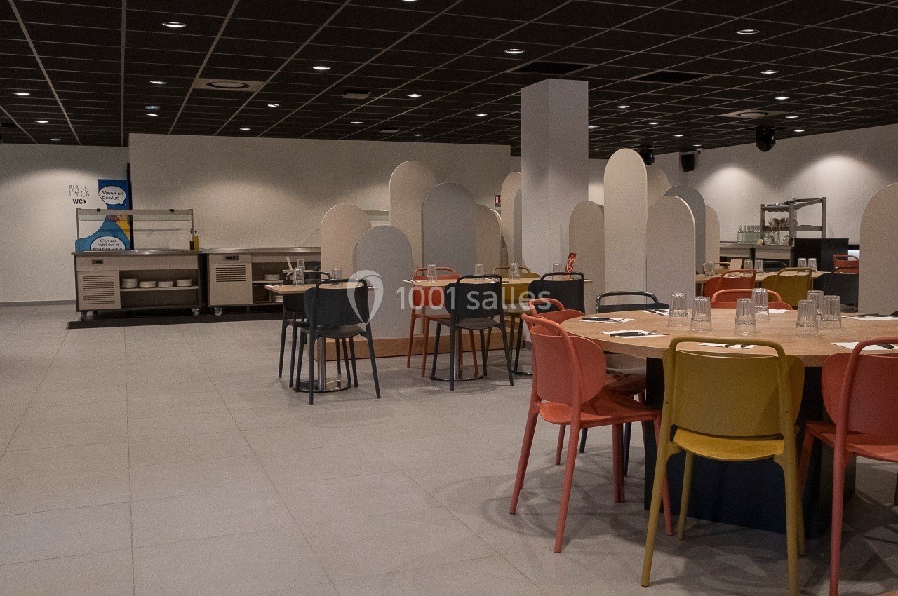 Location salle Marines (Val-d'Oise) - Stand Ing Events #7 Salle de restaurant moderne avec tables rondes, chaises colorées et cloisons de séparation sous un plafond noir.