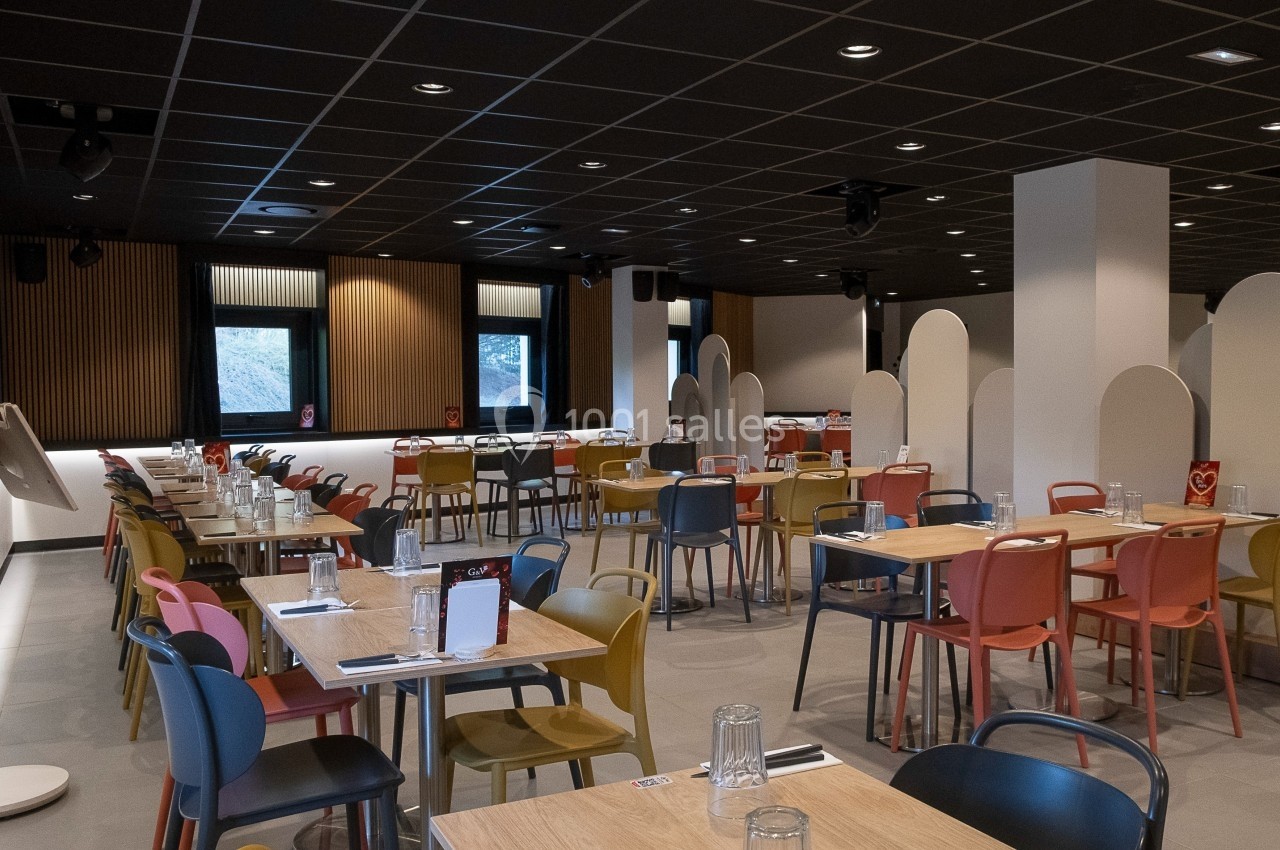 Location salle Marines (Val-d'Oise) - Stand Ing Events #9 Salle de restaurant moderne avec tables en bois, chaises colorées et cloisons séparatrices sous un plafond sombre.