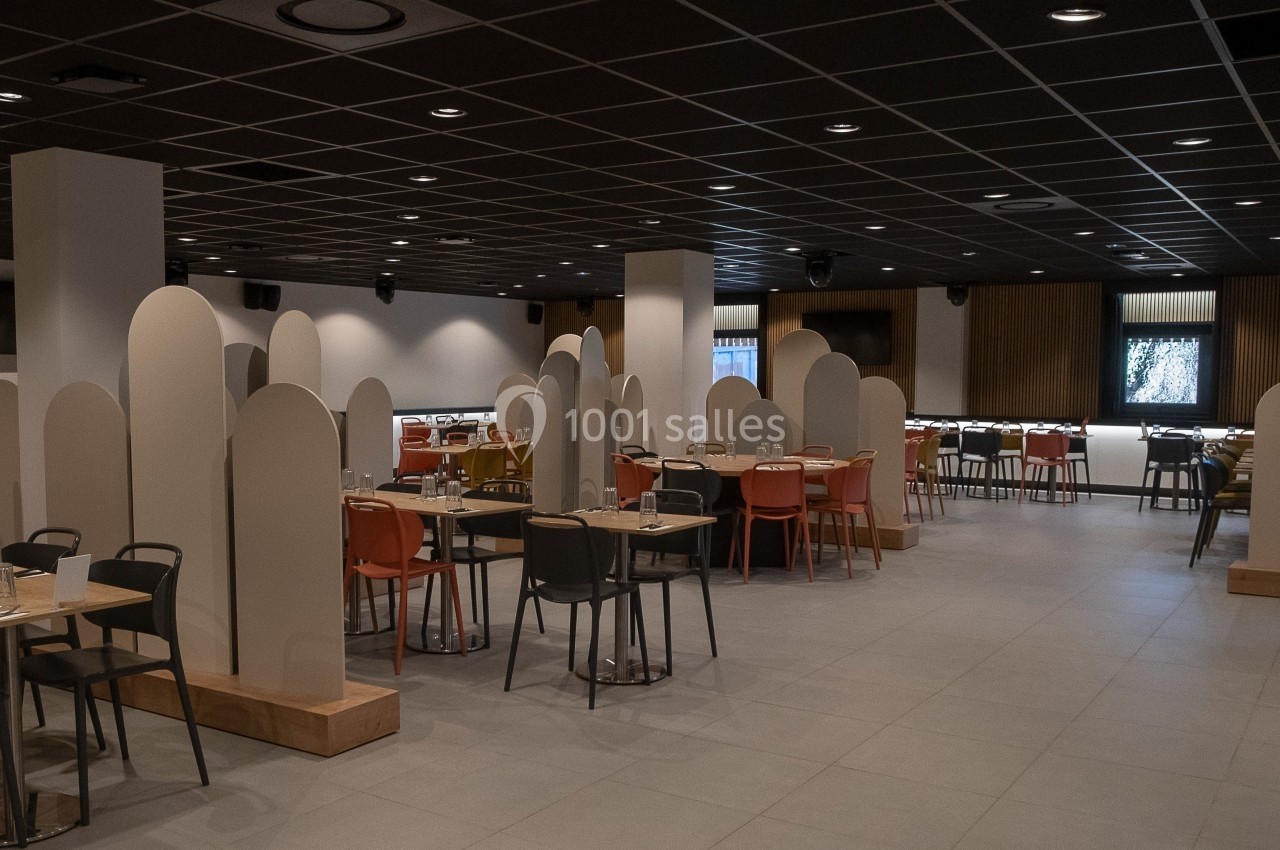 Location salle Marines (Val-d'Oise) - Stand Ing Events #13 Salle de restaurant moderne avec des tables espacées, des chaises colorées et des séparateurs en forme d'arche.