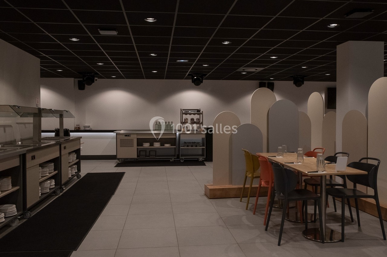 Location salle Marines (Val-d'Oise) - Stand Ing Events #14 Salle de restauration moderne avec tables, chaises colorées, buffet en libre-service et cloisons décoratives.