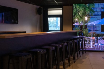 Miniature Location salle Marines (Val-d'Oise) - Stand Ing Events #17 Salle moderne avec tables hautes, éclairage tamisé, et mur décoré d'une scène urbaine nocturne avec un bistrot.