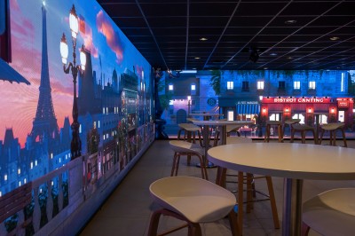 Miniature Location salle Marines (Val-d'Oise) - Stand Ing Events #24 Salle moderne avec tables hautes, éclairage tamisé, et mur décoré d'une scène urbaine nocturne avec un bistrot.