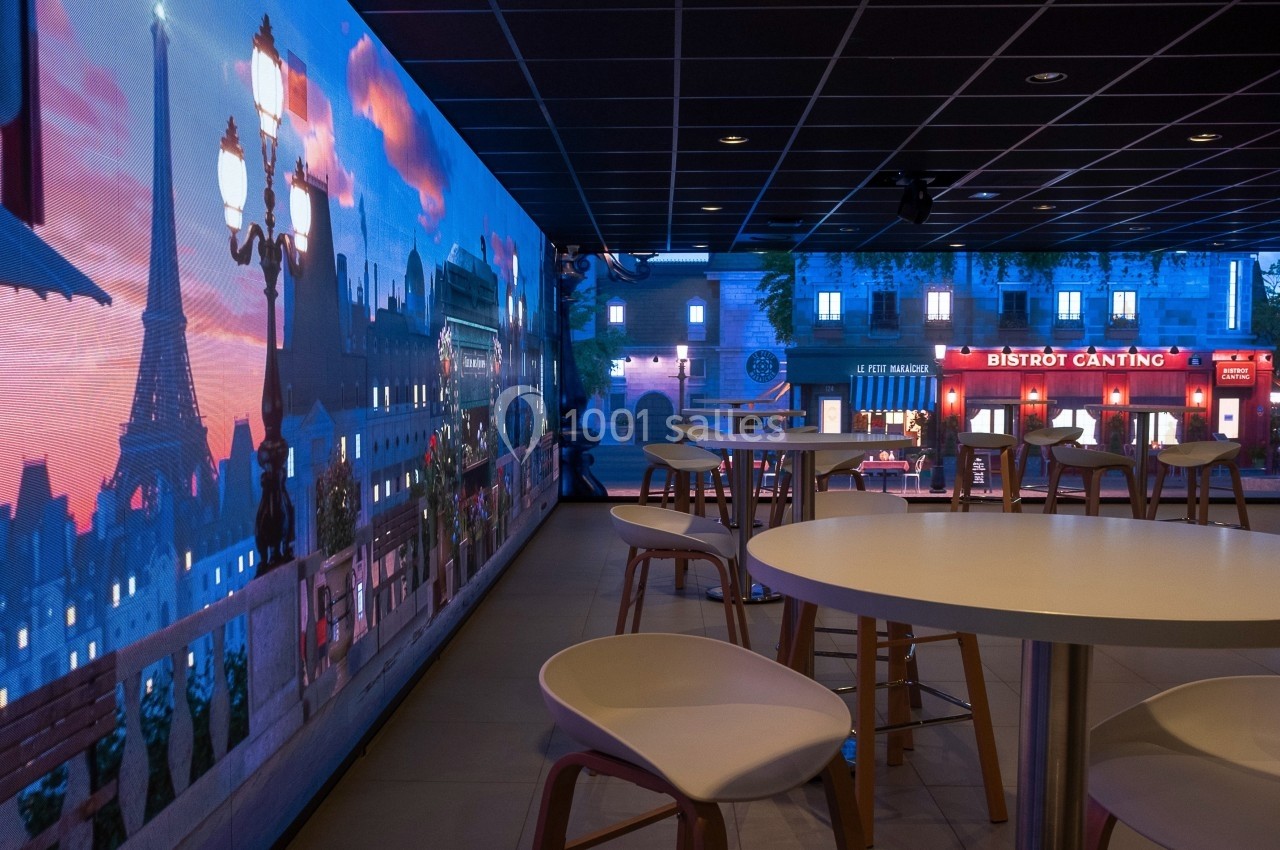 Location salle Marines (Val-d'Oise) - Stand Ing Events #24 Salle moderne avec tables et chaises, décorée d'une fresque lumineuse représentant une vue parisienne avec la tour Eiffel.