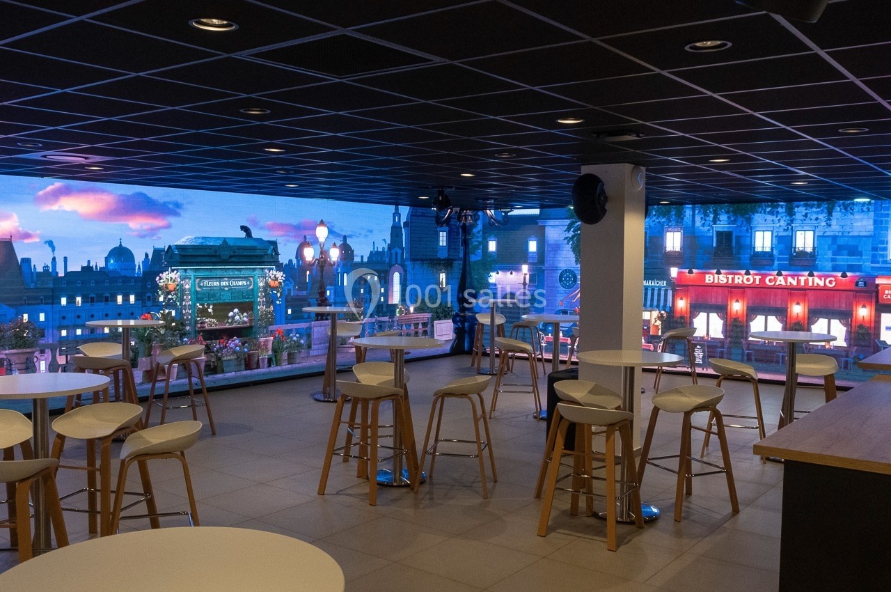 Location salle Marines (Val-d'Oise) - Stand Ing Events #29 Salle avec des tables et tabourets, décorée d'une vue immersive représentant une rue parisienne éclairée.