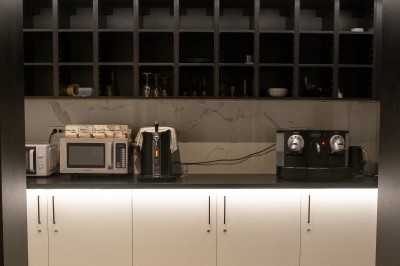 Salle de bain moderne avec lavabo, miroir rond, mur en carrelage noir et blanc, et éclairage tamisé.