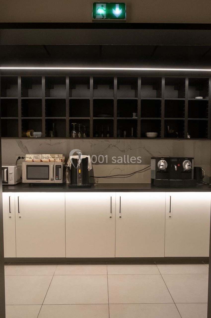 Cuisine moderne avec rangements ouverts, micro-ondes, grille-pain, cafetière et machine à café sur un plan de travail.