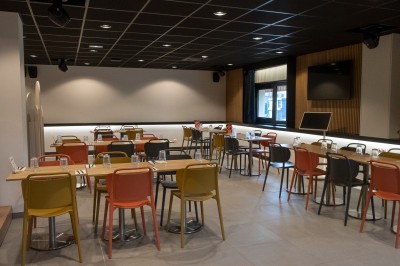 Salle de bain moderne avec lavabo, miroir rond, mur en carrelage noir et blanc, et éclairage tamisé.