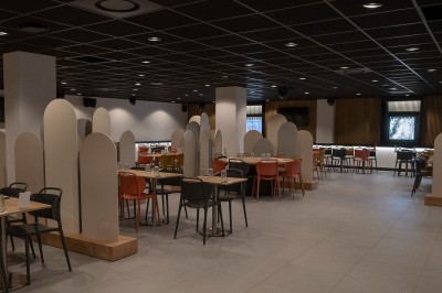 Salle de bain moderne avec lavabo, miroir rond, mur en carrelage noir et blanc, et éclairage tamisé.