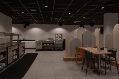 Salle de bain moderne avec lavabo, miroir rond, mur en carrelage noir et blanc, et éclairage tamisé.