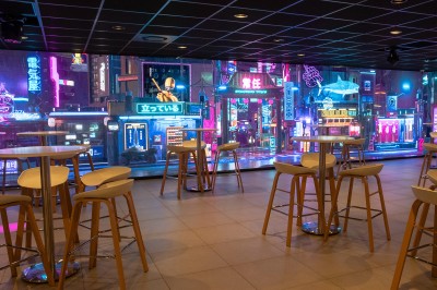 Salle de bain moderne avec lavabo, miroir rond, mur en carrelage noir et blanc, et éclairage tamisé.