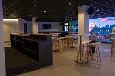 Salle de bain moderne avec lavabo, miroir rond, mur en carrelage noir et blanc, et éclairage tamisé.