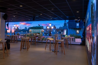 Salle de bain moderne avec lavabo, miroir rond, mur en carrelage noir et blanc, et éclairage tamisé.