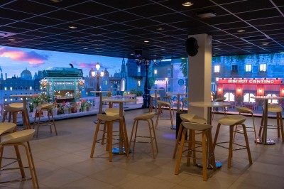 Salle de bain moderne avec lavabo, miroir rond, mur en carrelage noir et blanc, et éclairage tamisé.